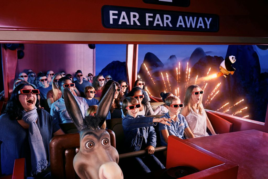 3D 안경을 쓴 사람들은 당나귀 캐릭터를 앞에 두고 산과 조명을 배경으로 실내 라이딩을 즐깁니다. 'FAR FAR FAR' 표시가 보입니다.