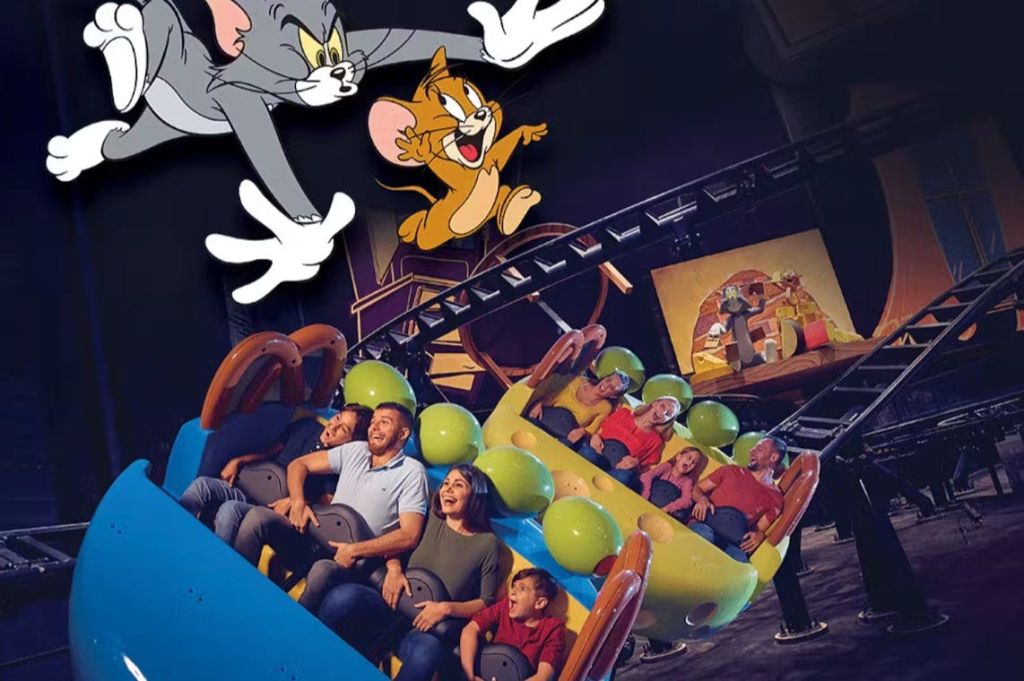 톰과 제리 캐릭터가 그려진 실내에서 다채로운 롤러코스터를 즐기는 사람들의 모임.