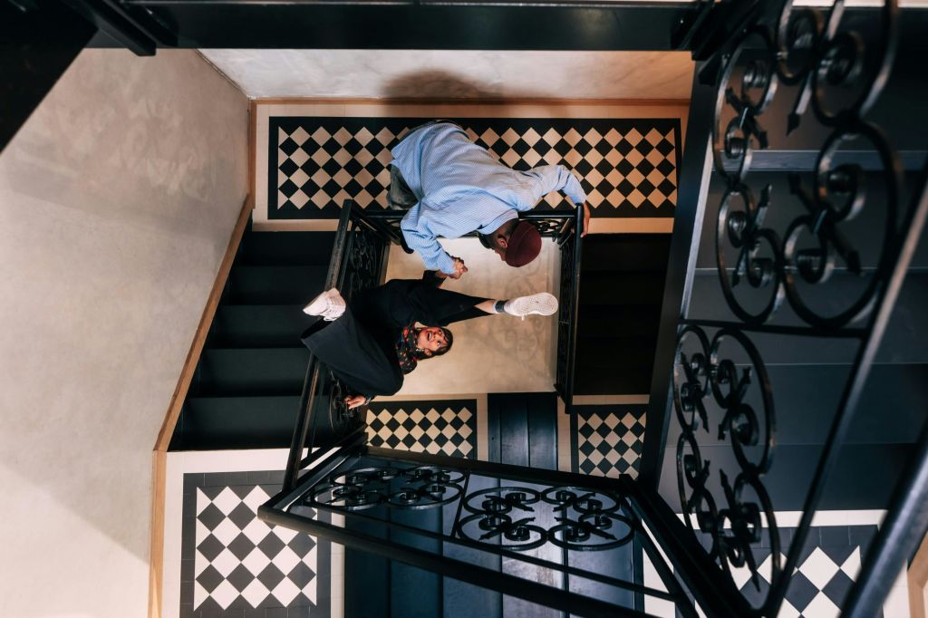 위에서 바라본 검은색과 흰색 타일 바닥이 있는 장식용 계단에서 상호작용하는 두 사람.