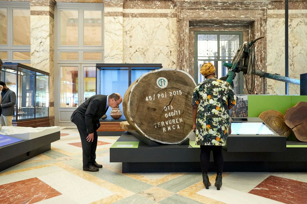 한 박물관의 두 사람이 커다란 나무 단면에 글씨가 새겨져 있고 진열 케이스에 둘러싸여 있습니다.