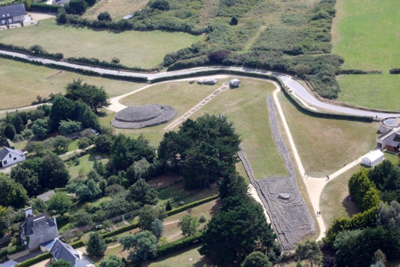 고대 석조 언덕, 길, 나무가 있는 잔디가 우거진 풍경을 공중에서 감상할 수 있습니다.