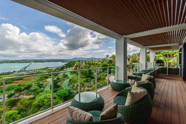 푸른 고리버들 의자와 베이지색 쿠션으로 꾸며진 테라스에서는 푸른 녹음과 바위, 흐린 하늘 아래 물결이 한눈에 들어옵니다.