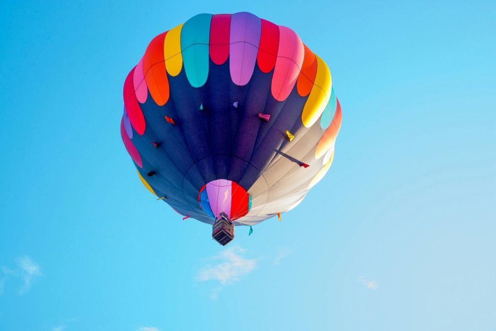 선명한 파란색 배경 아래 바구니가 있는 하늘의 다채로운 열기구.