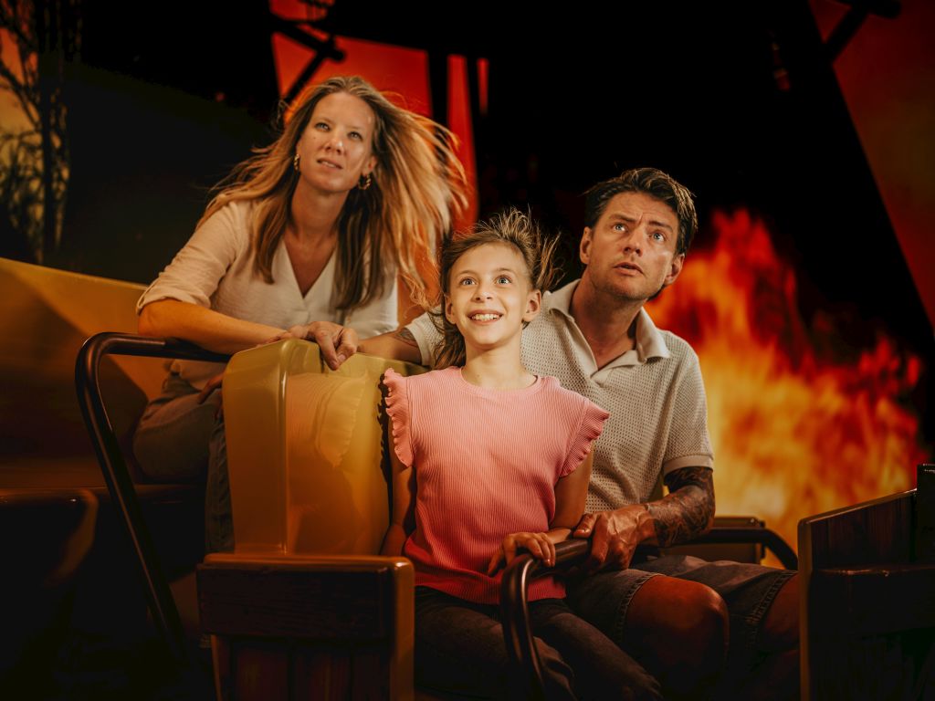 불타는 배경에 대한 흥분과 경외감의 표정으로 놀이기구를 타고 있는 3인 가족.