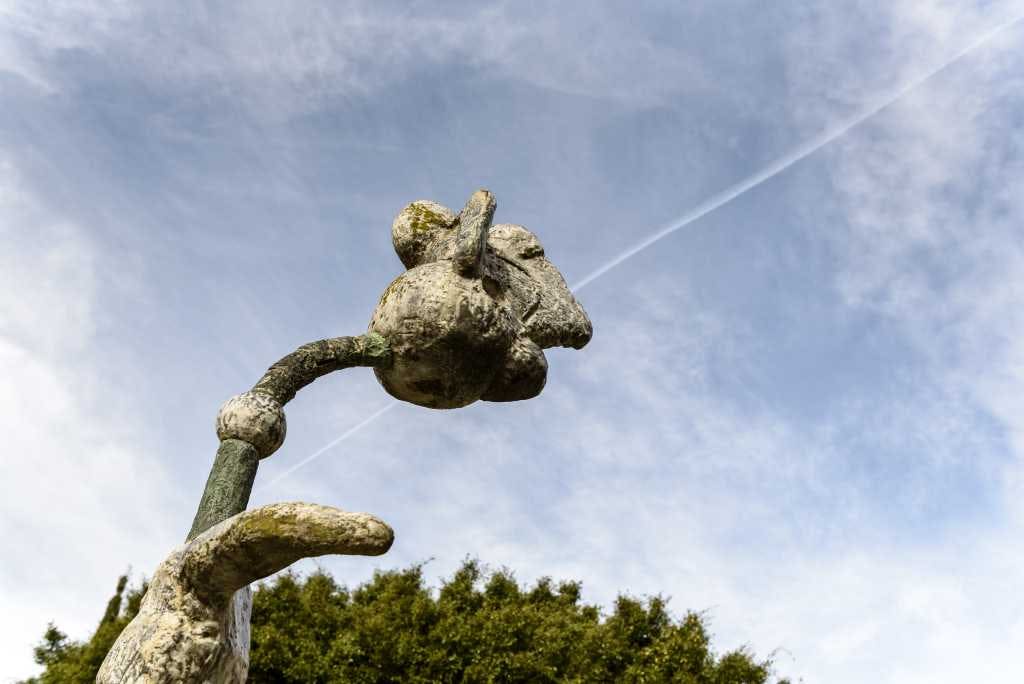 푸른 하늘 아래 연한 구름과 눈에 띄는 나무 선이 있는 꽃의 풍화된 돌 조각.