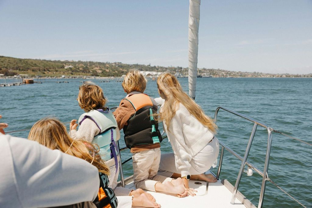 멀리 바다사자를 가리키는 범선 활을 탄 여성과 세 명의 어린이