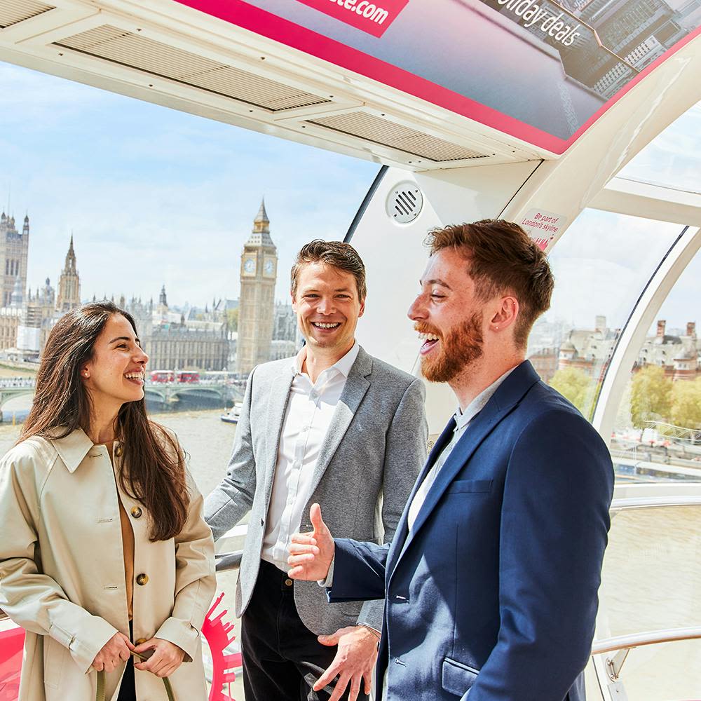 빅벤과 국회의사당을 배경으로 런던 아이 캡슐 안에서 세 사람이 웃으며 이야기를 나누고 있습니다.