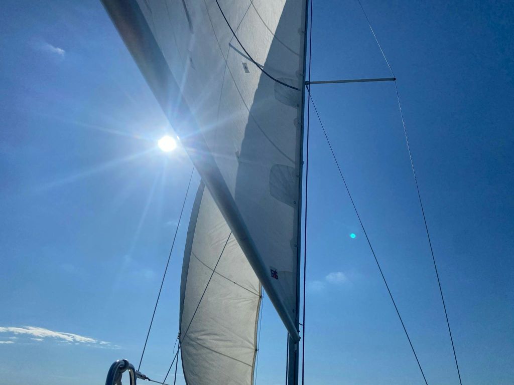 햇살이 내리쬐는 푸른 하늘을 배경으로 눈부시게 빛나는 리깅과 밝은 햇살이 어우러진 요트.