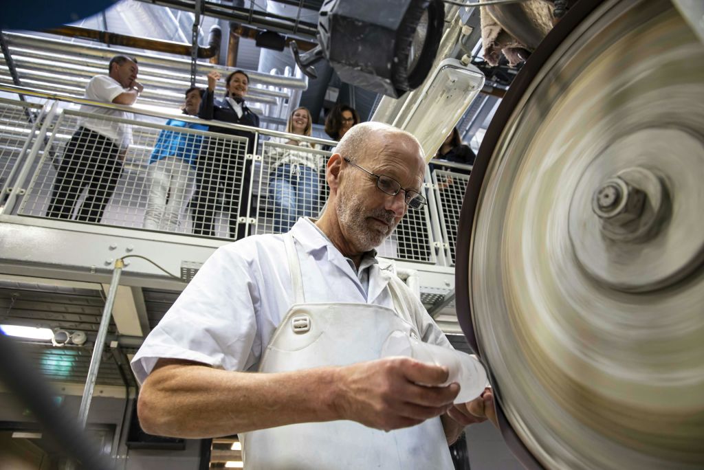 흰 코트를 입은 대머리 남자는 기계로 작업하고, 일행은 위의 발코니에서 관찰합니다.