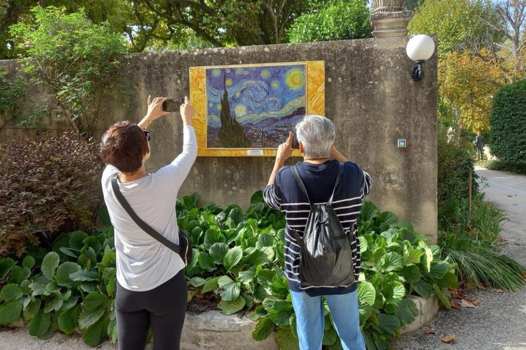 빈센트 반 고흐 (Vincent Van Gogh) 의 그림이 있는 명판 사진을 찍는 것을 뒤에서 본 두 사람