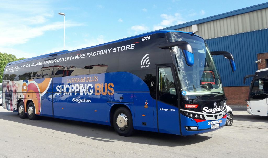 건물 외부에 무료 와이파이 광고가 있는 파란색과 검은색 버스가 "LA ROCA del VALLÈS SHOPPING BUS Sagales" 라고 표시되어 있습니다.