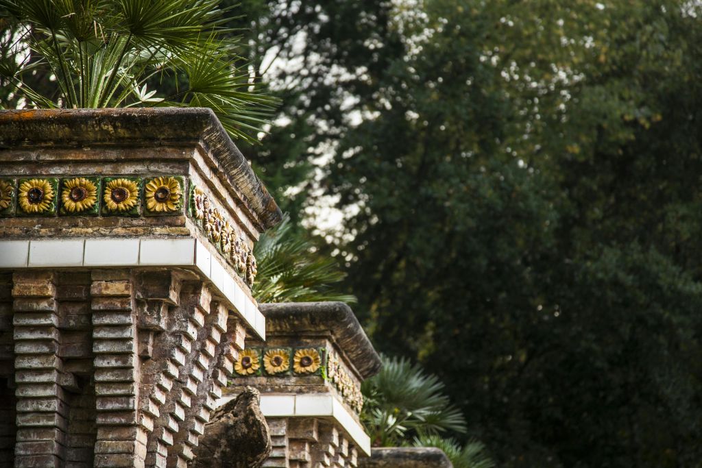 해바라기 타일로 장식된 벽돌 구조는 울창한 녹지로 둘러싸여 있으며, 그 꼭대기에는 야자수 프론드가 보입니다.