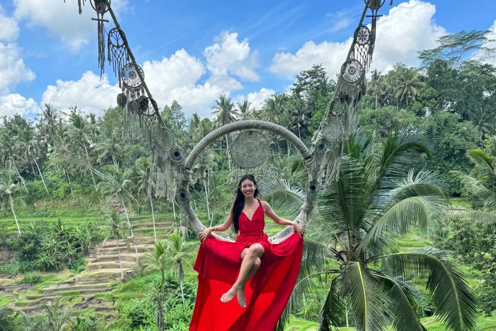 유 펀 필드 파크 (U Fun Field Park) 의 아름다운 푸른 계단식 논 위에서 드림캐쳐 스윙 (Dreamcatcher Swing) 을 입고 빨간색 롱 드레스를 입은 여성