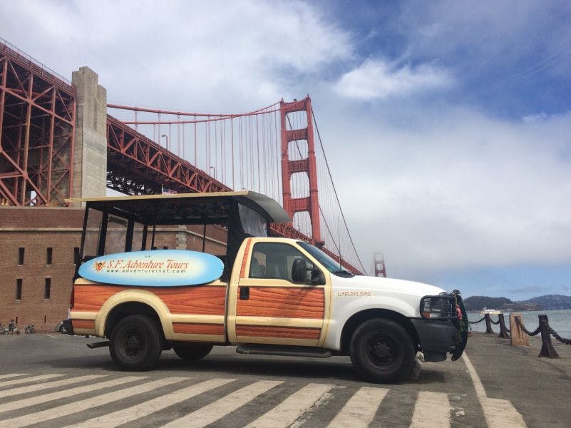 "S.F. 어드벤처 투어" 가 있는 투어 차량은 흐린 날 금문교 근처에 주차되어 있습니다.