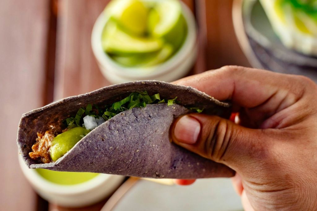 바나나 잎으로 감싼 고소한 필링이 들어간 푸른 옥수수 또띠아 타코.