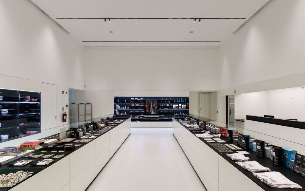 다양한 아이템이 진열된 두 개의 긴 흰색 카운터와 선반을 배경으로 한 모던하고 미니멀한 매장 인테리어.