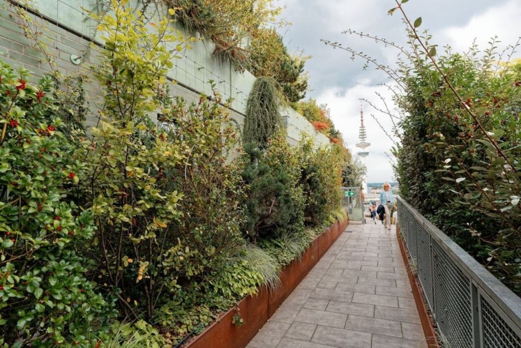 푸르름과 꽃이 어우러진 산책로를 지나면 저 멀리 탑이 한눈에 들어옵니다. 두 사람이 걸어가고 있습니다.