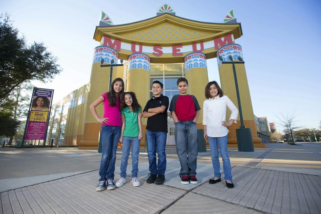 커다란 '박물관' 표지판이 있는 건물 앞에 5명의 어린이가 웃으며 서 있습니다.