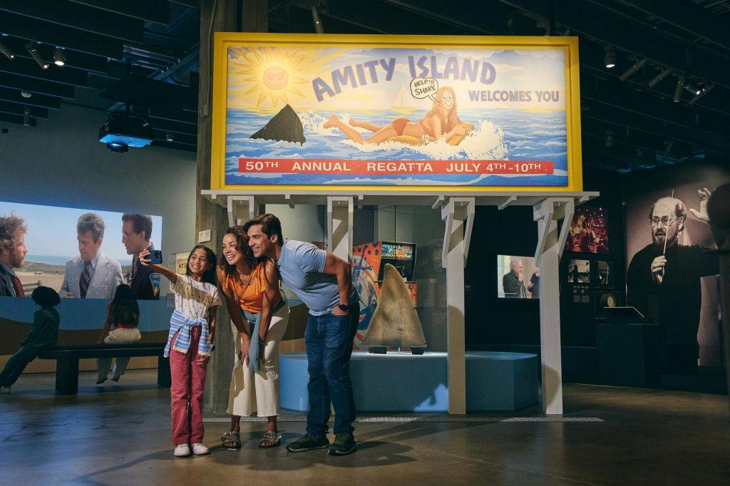 친밀도 섬 표지판과 상어 관련 테마가 있는 전시회에서 셀카를 찍는 세 사람으로 구성된 그룹.