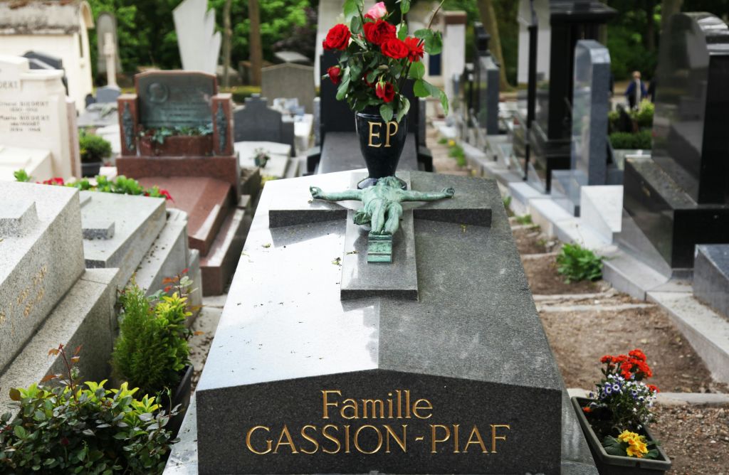 청동 십자가와 붉은 장미 꽃병으로 장식된 비석에 "Famille Gassion-Piaf" 가 새겨져 있습니다.