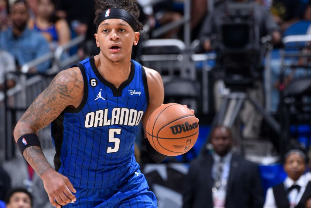 코트에서 미드 액션으로 농구를 들고 있는 파란색 올랜도 유니폼을 입은 농구 선수.
