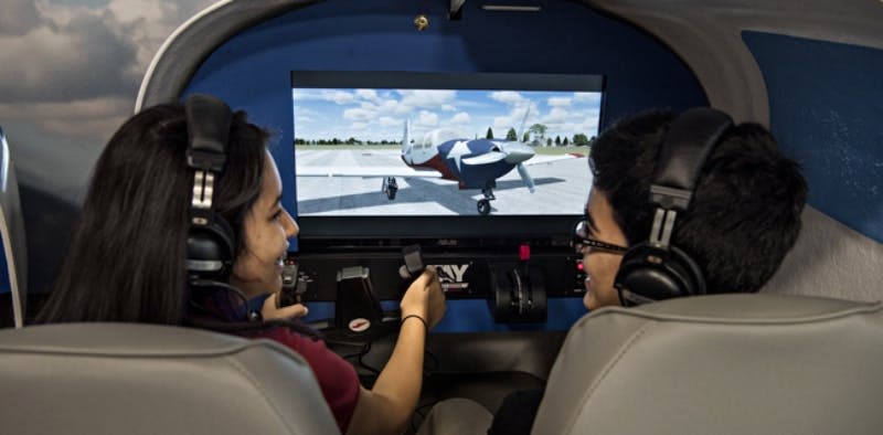 활주로에서 비행기를 표시하는 화면에 초점을 맞추면서 헤드폰을 착용하고 비행 시뮬레이터를 작동하는 사람.