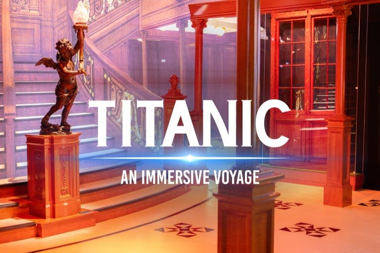 "Titanic: An Immersive Voyage" 텍스트 오버레이가 있는 재현된 타이타닉 그랜드 계단의 내부 장면.
