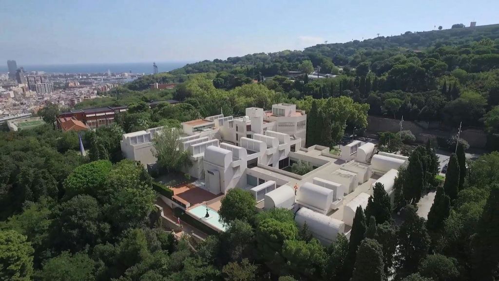 언덕이 우거진 풍경과 바다를 배경으로 녹음으로 둘러싸인 흰색의 현대적인 건물.