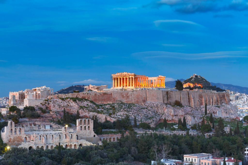 황혼의 하늘을 배경으로 멀리서 바라본 그리스 아테네의 아크로폴리스 꼭대기에서 빛나는 파르테논 신전.