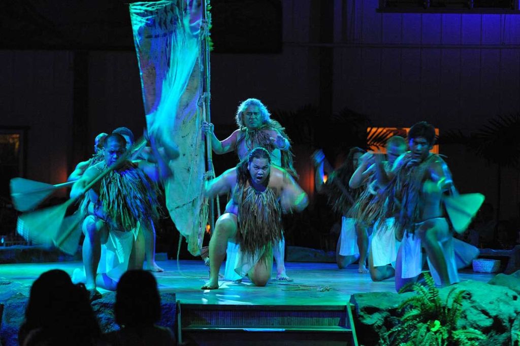 전통 복장을 한 공연자들은 무대에서 활기찬 파란색과 녹색 조명을 배경으로 활기차게 춤을 춘다.