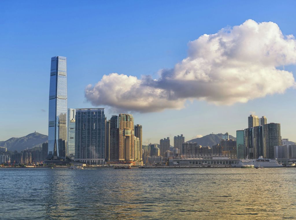 높은 건물과 하늘에 커다란 구름이 있는 도시의 스카이라인이 물 건너편에 보입니다.