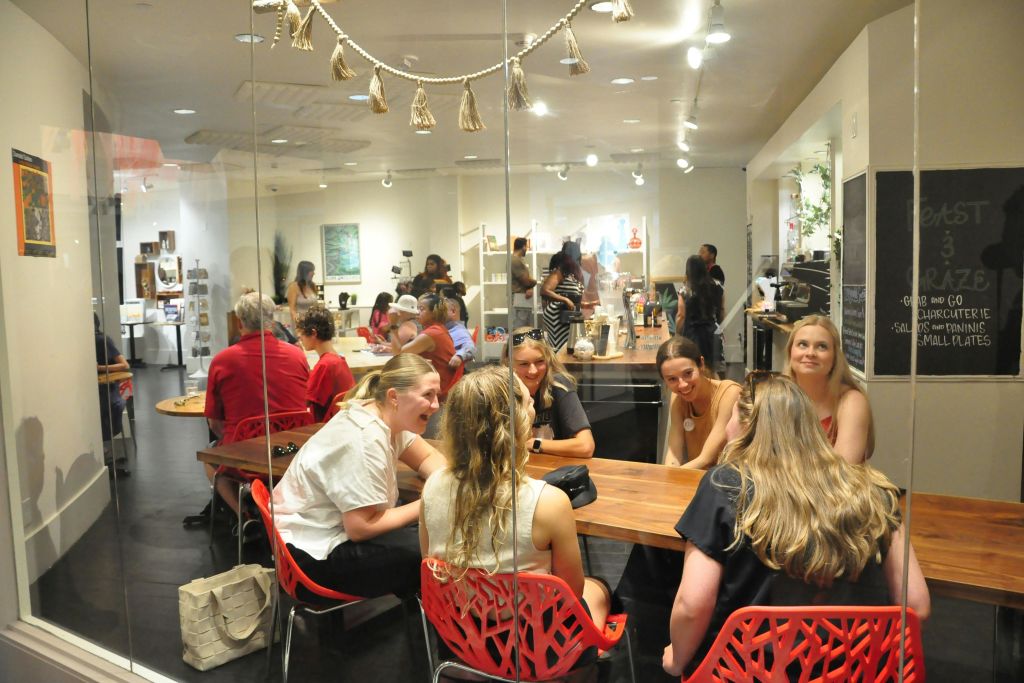 유리 패널을 통해 바라보는 카페의 모습과 서로의 동행을 즐기는 친구들의 테이블