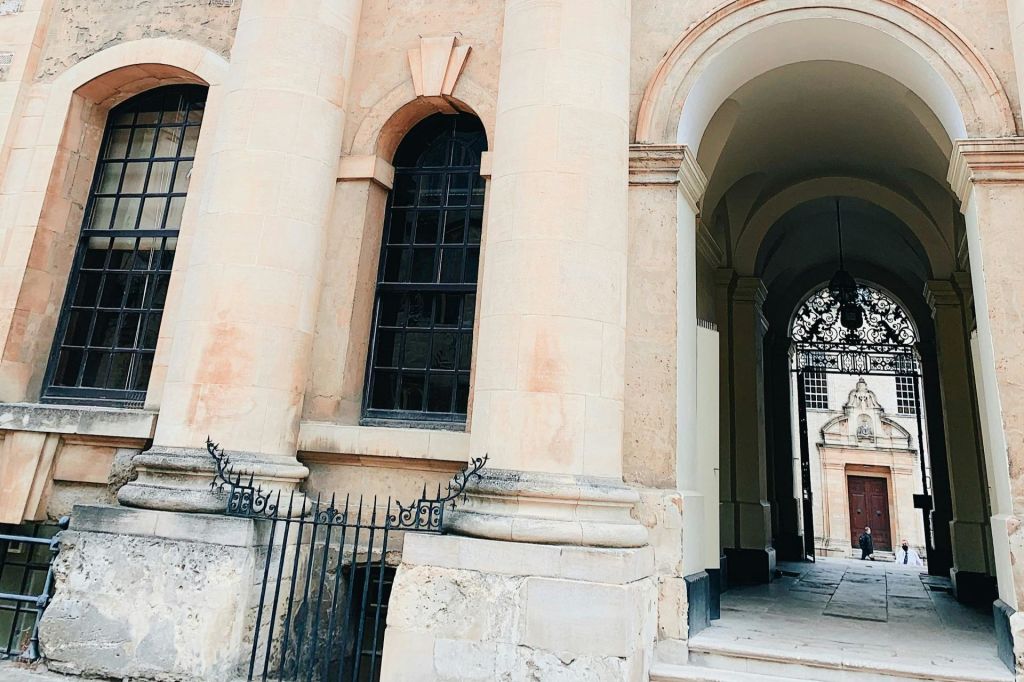 아치형 창문과 출입구가 있는 유서 깊은 건물로 연철문과 석조 기둥이 특징입니다.