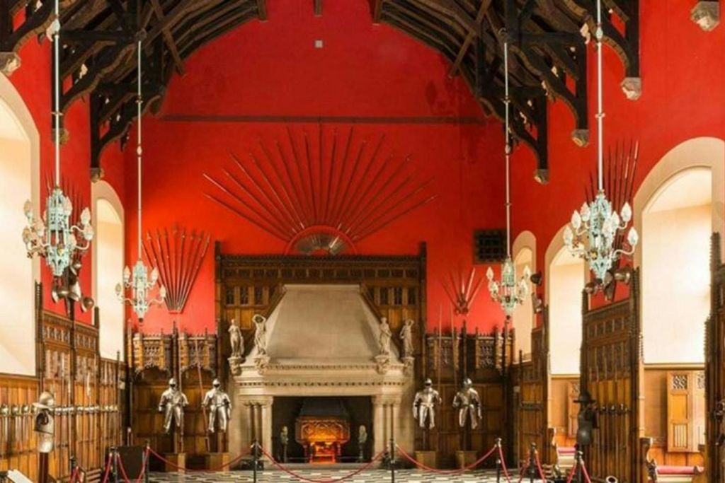 붉은 벽에 커다란 벽난로, 벽에 진열된 검, 갑옷이 진열된 대강당.