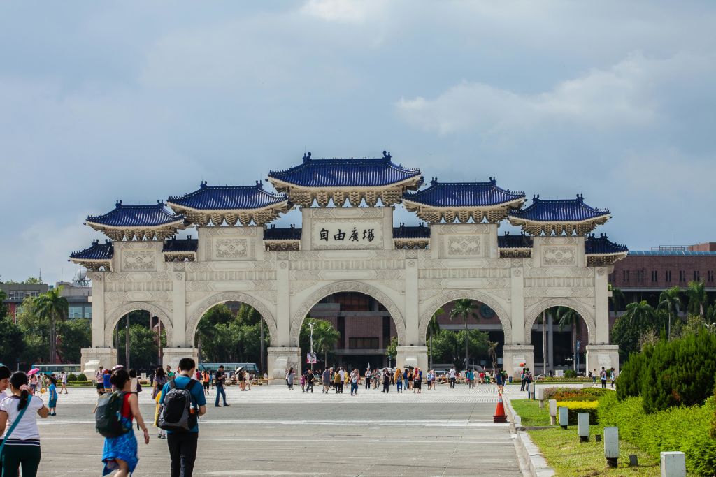 넓은 광장에 자리한 파란색 타일로 마감된 지붕과 한자가 있는 크고 화려한 아치형 통로 아래를 걸어보세요.