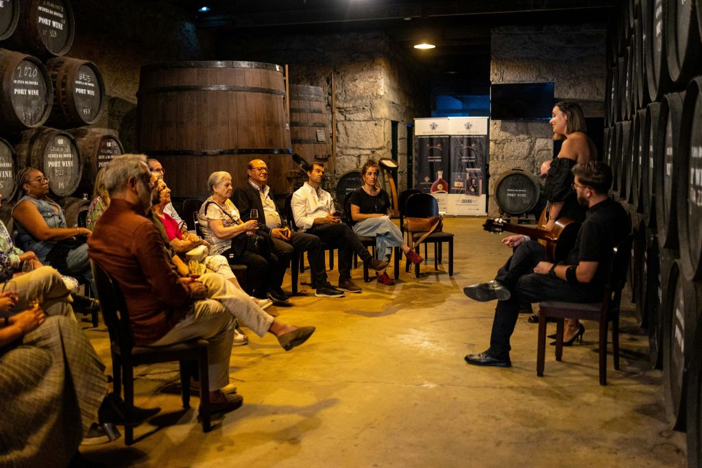 사람들은 커다란 나무 통과 돌담이 있는 소박한 방의 의자에 앉아 보이지 않는 스피커의 말을 주의 깊게 듣습니다.