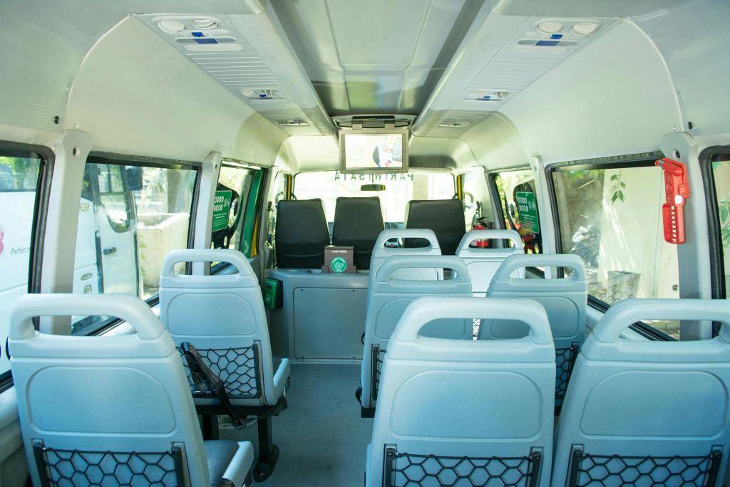 연한 회색의 빈 좌석이 줄지어 있고, 커다란 창문과 전면 스크린이 있는 작은 버스의 내부.