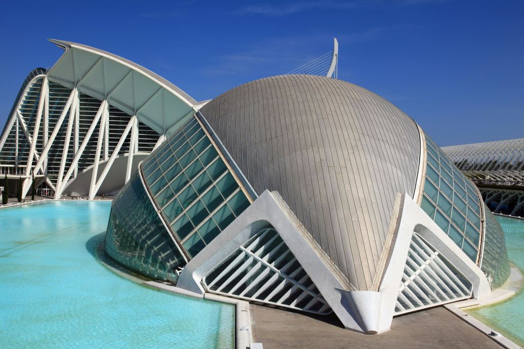 돔 형태, 커다란 유리 패널, 맑고 푸른 하늘 아래 주변의 물이 어우러진 미래형 건물.