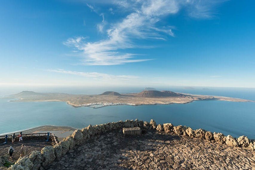 해안선이 내려다보이는 석조 벤치, 먼 산, 지혜로운 구름이 있는 맑고 푸른 하늘이 있는 바위 전망대.