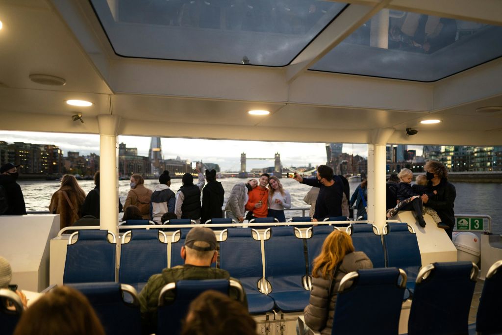 보트에 탑승한 승객, 난간에 서 있는 승객, 타워 브리지를 배경으로 한 승객.