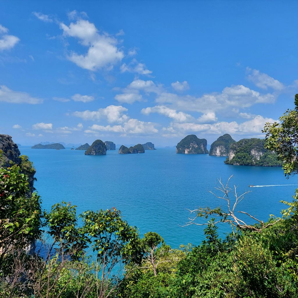 푸른 하늘 아래 흩어져 있는 바위섬과 청록색 바다의 고요한 풍경을 감상할 수 있습니다.