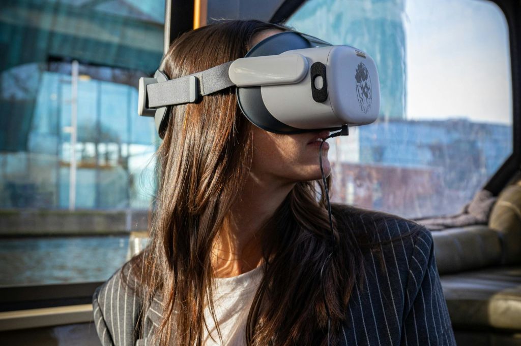 가상 현실 헤드셋을 착용하고 옆을 바라보는 사람. 배경은 유리와 야외 경치를 보여줍니다.