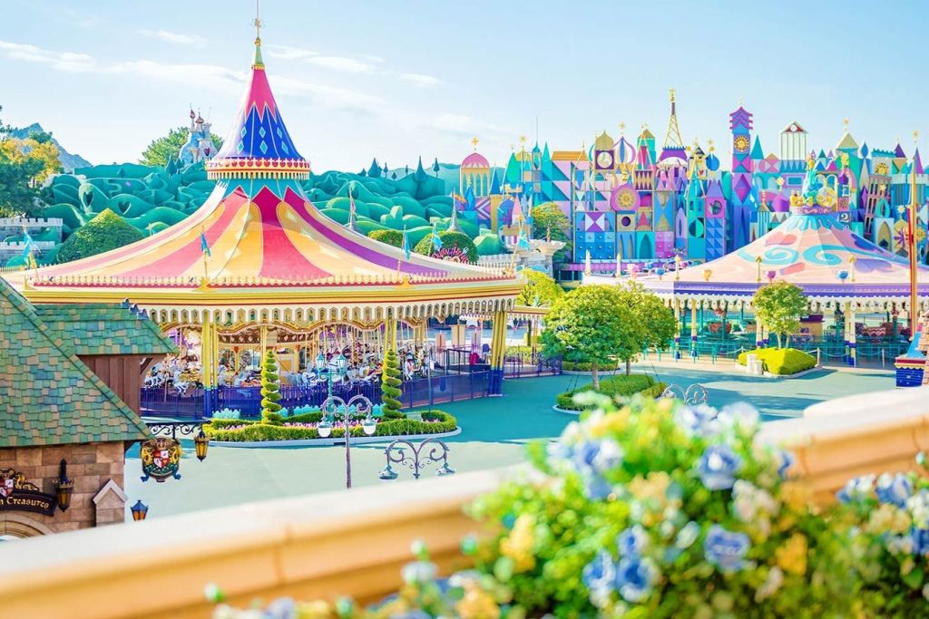 화창한 날에는 빨간색과 노란색 텐트 아래 회전목마, 기발한 건물, 울창한 녹지가 있는 밝은 색상의 놀이공원.