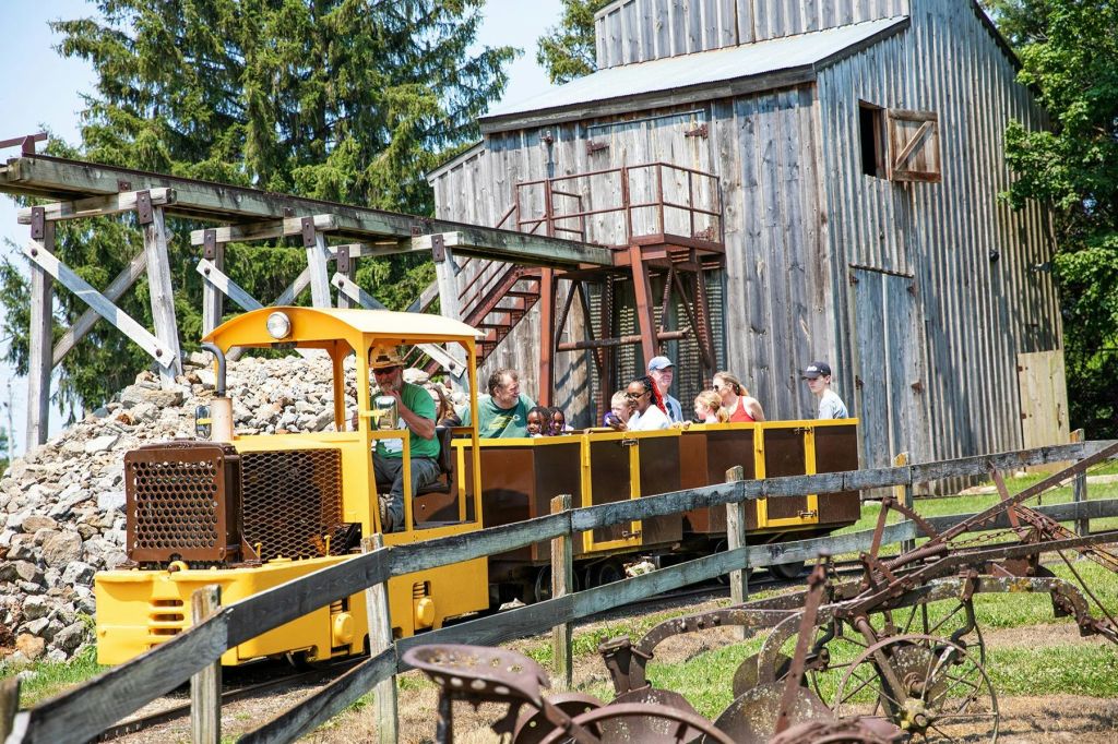 박물관 캠퍼스 주변에서 기차를 타세요. 배경에 있는 헤드프레임 건물도 투어의 일부입니다.