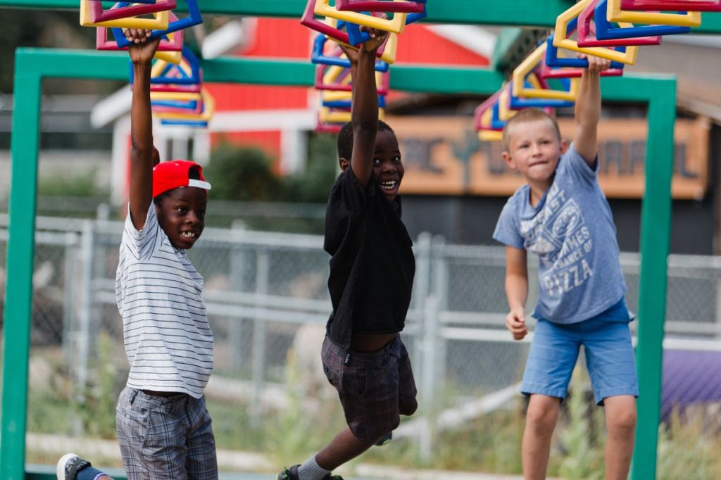 야외 놀이터에서 화려한 오버헤드 클라이밍 바에 매달려 놀고 있는 두 소년.