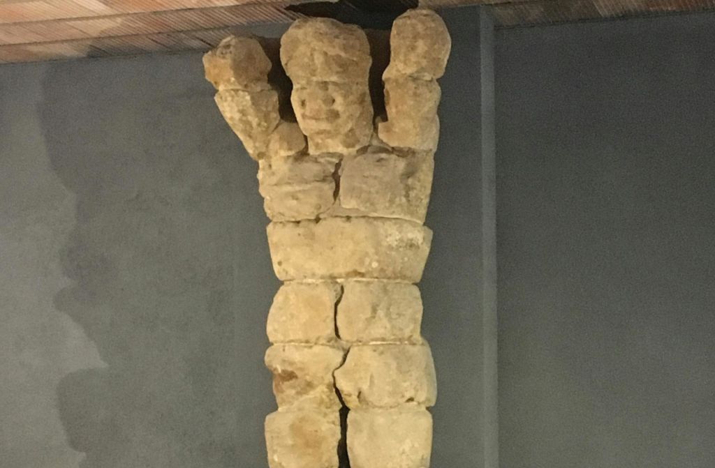 평평한 벽에 팔을 올린 사람의 모습을 닮은 불규칙한 석조 블록을 쌓아 올린 조형물.