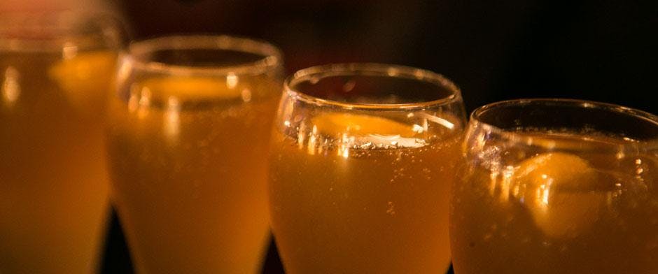 작은 거품과 따뜻한 조명이 있는 밝은 황금색 액체 (맥주 또는 사과주) 로 채워진 두 잔의 클로즈업.