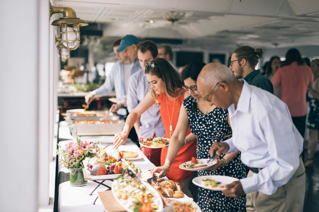 다양한 요리와 함께 뷔페에서 자신을 서빙하는 사람들. 실내 행사나 모임으로 보입니다.