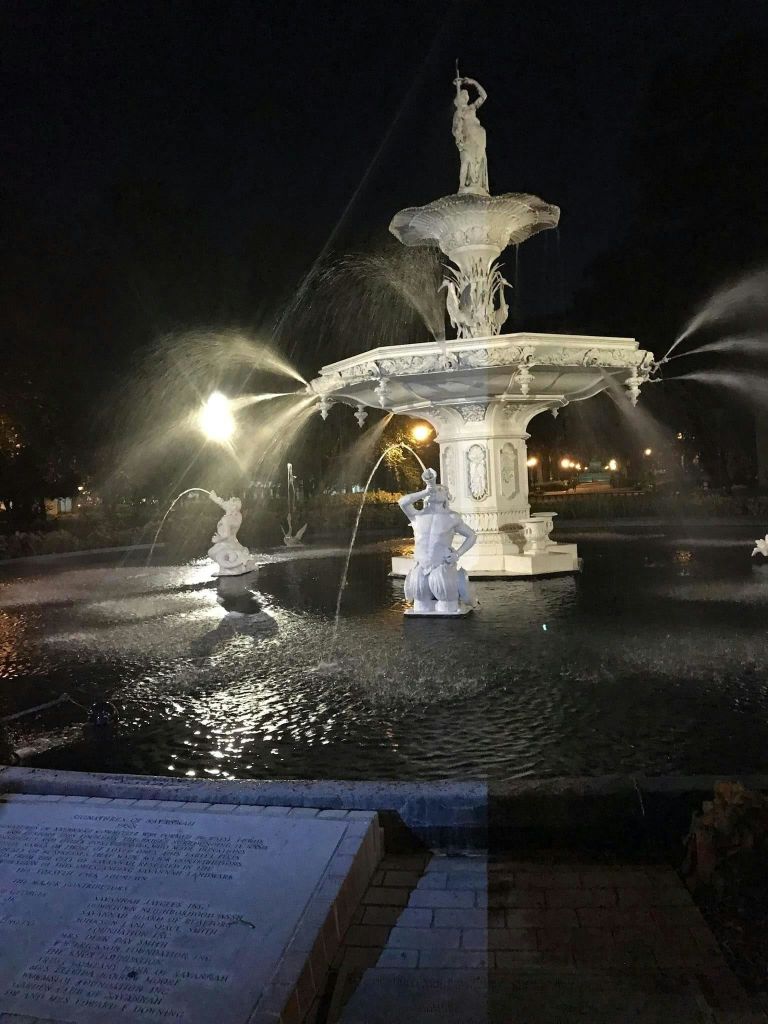 어두운 배경에 조각상과 물이 흐르는 밤의 분수.