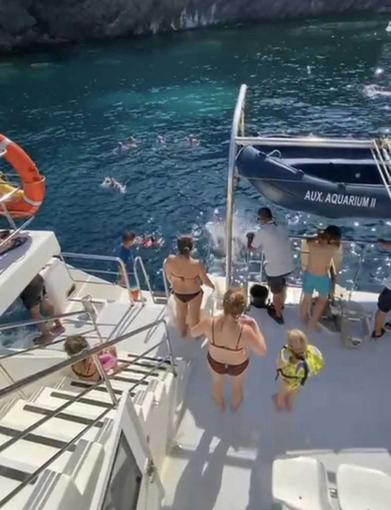 보트에서 수영복을 입고 옆 푸른 물에서 다이빙이나 수영을 즐기는 사람들. "AUX" 라고 표시된 작은 보트. 수족관 II "가 보입니다.